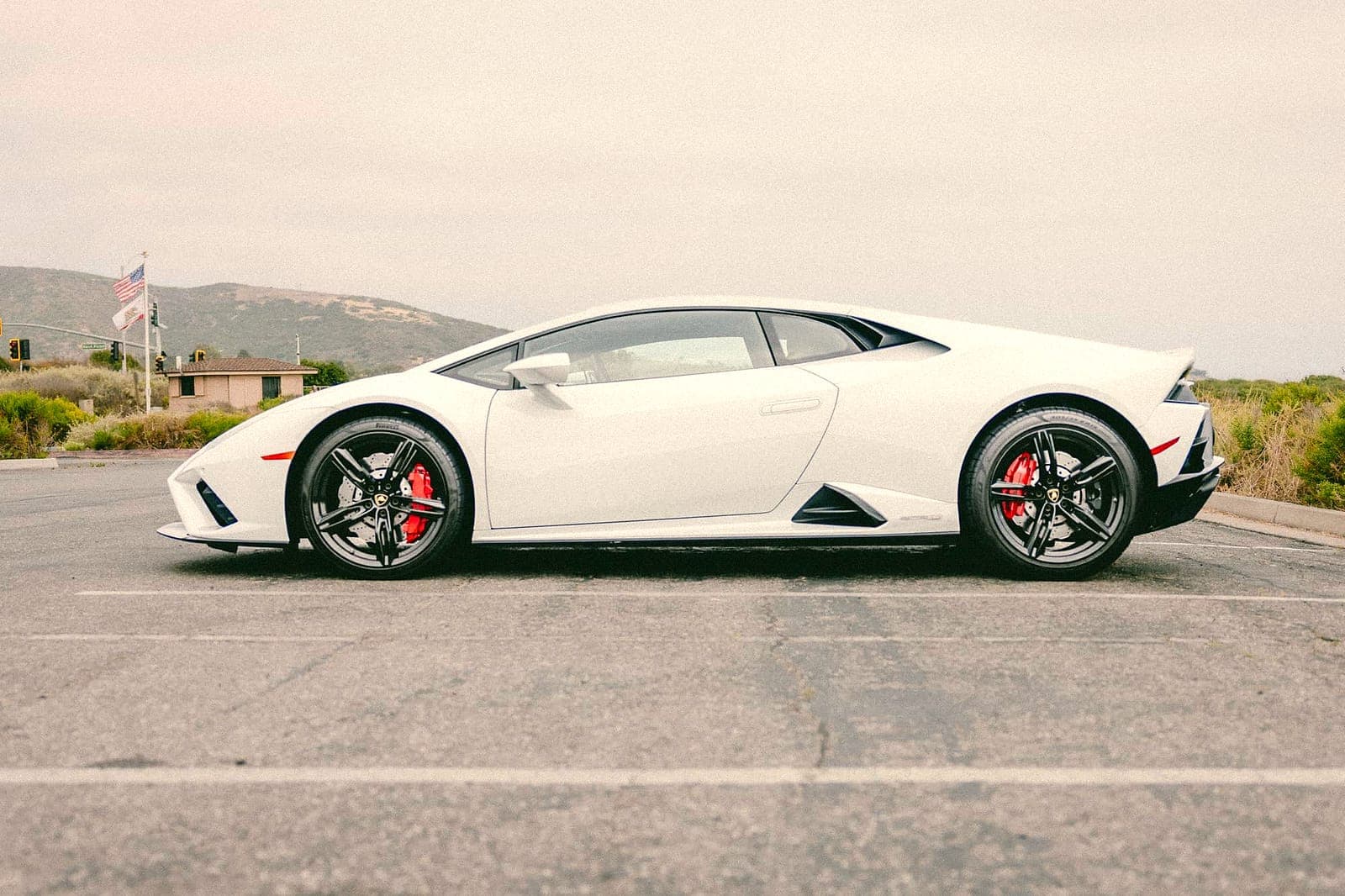White Lamborghini Huracán coupe in profile on an Orange County road