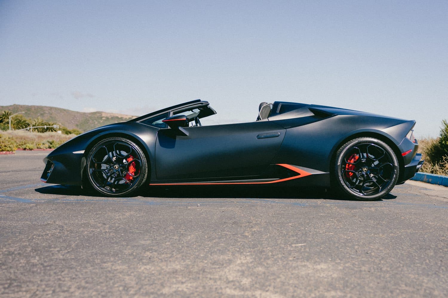 Matte-black Lamborghini Huracán EVO Spyder in profile, top down, on an Orange County lot