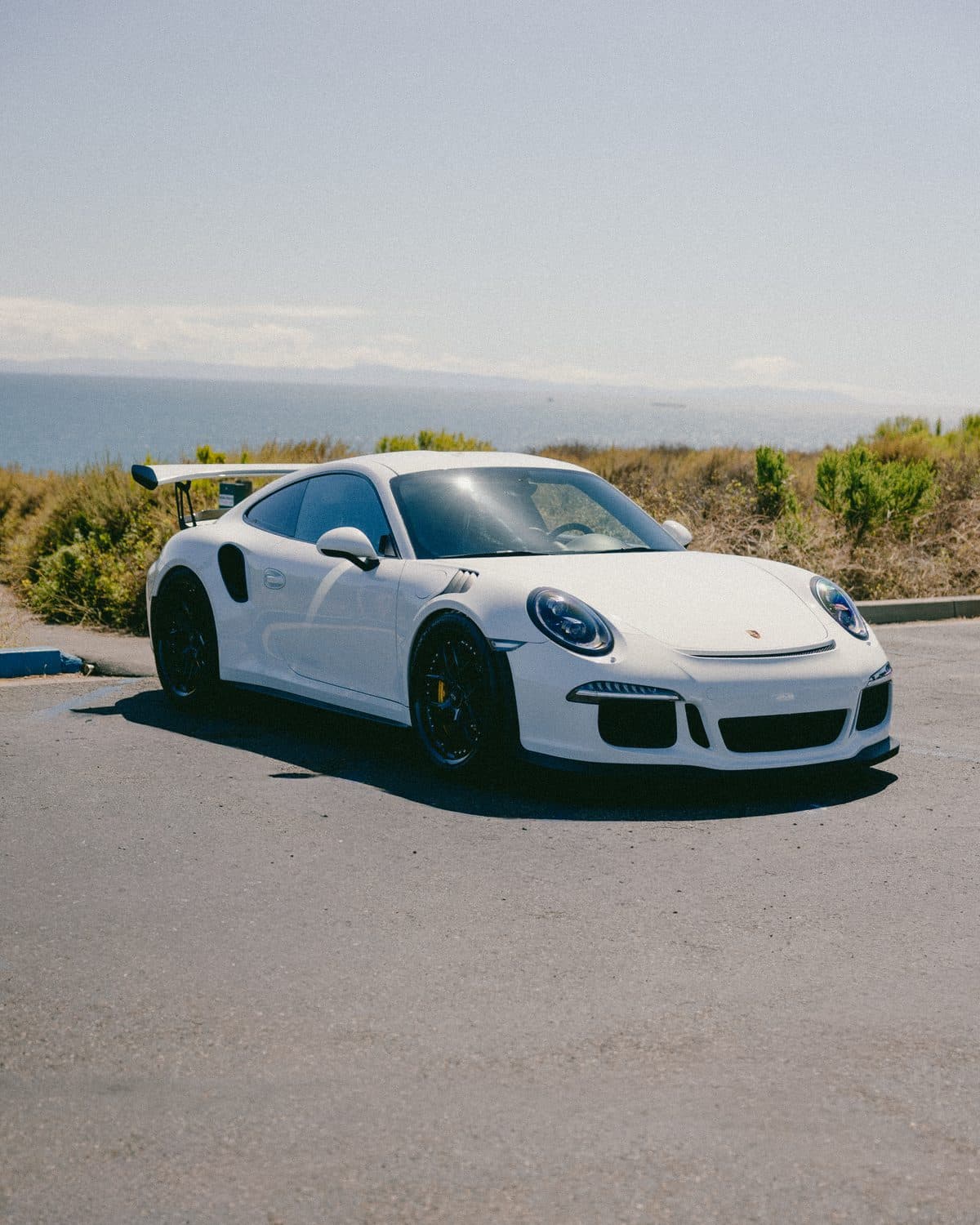 White Porsche 911 GT3 RS, passenger-side front three-quarter on the coast