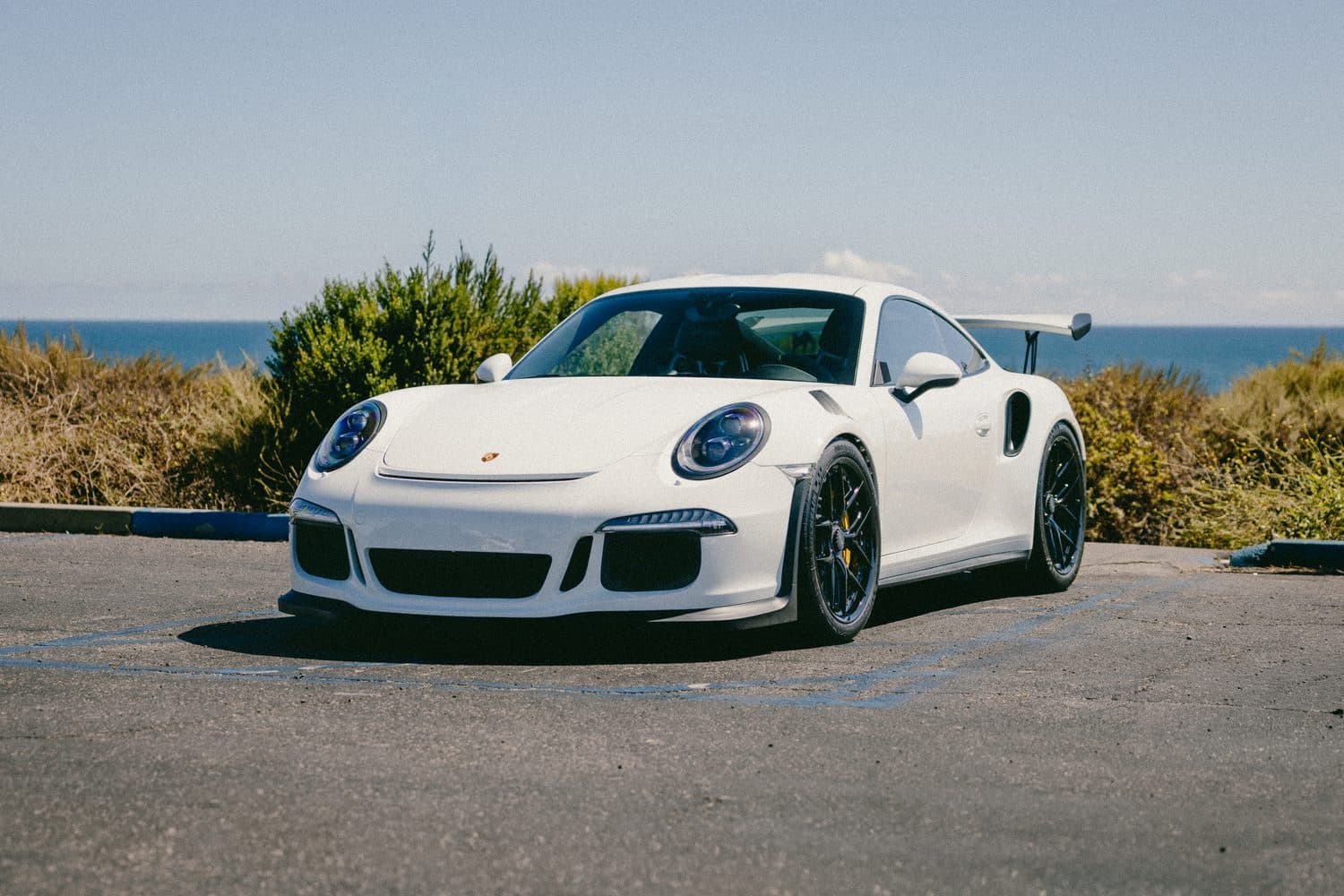 White Porsche 911 GT3 RS, front three-quarter on the Orange County coast