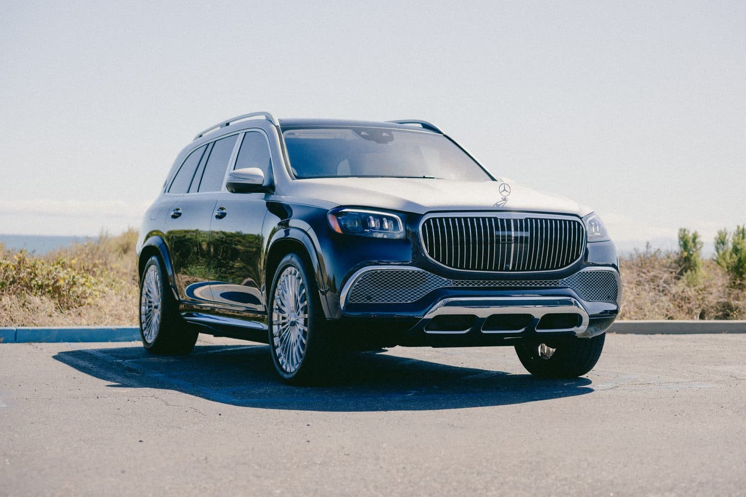 Black Mercedes-Maybach GLS, tight front three-quarter showing the chrome vertical-slat Maybach grille, LED headlight and front wheel